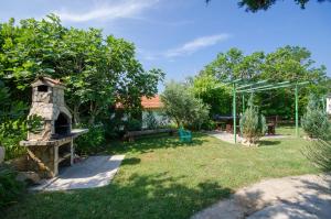 a garden with a stone oven in the grass at Apartments Ivan in Lopar