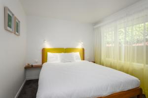 a bedroom with a large white bed and a window at Adelphi Motel in Christchurch