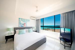 a bedroom with a bed and a large window at Pinnacles in Airlie Beach