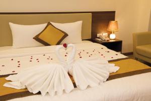 two swans dressed in white are sitting on a bed at Hùng Mạnh Plaza Hotel in Hương Tân Lạc