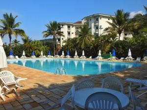 a large swimming pool with chairs and umbrellas at Ubatuba Apto. Wembley Tênis in Ubatuba