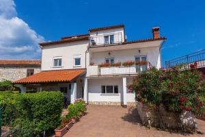 a large white house with a balcony and bushes at Casa Kujici in Krnica