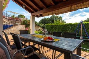 a wooden table and chairs on a patio with a playground at Casa Kujici in Krnica