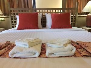 - deux serviettes assises au-dessus d'un lit dans l'établissement Pin Hotel, à Lampang