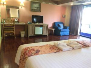 a bedroom with a bed and a tv and chairs at Pin Hotel in Lampang