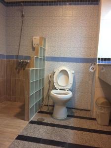a bathroom with a toilet in a tiled stall at Pin Hotel in Lampang