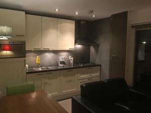 eine Küche mit weißen Schränken, einer Spüle und einem Tisch in der Unterkunft Fewo Klimduin Castricum in Castricum