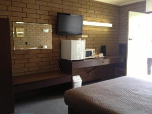 um quarto com uma televisão numa parede de tijolos em Rippleside Park Motor Inn em Geelong