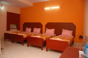 two beds in a room with orange walls at VENKKATRAMANAA RESIDENCY in Kumbakonam