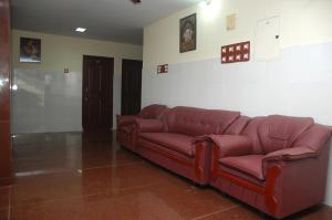 ein Wohnzimmer mit einer roten Couch in einem Zimmer in der Unterkunft VENKKATRAMANAA RESIDENCY in Kumbakonam