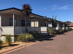 a house with a palm tree in front of a street at The Sundowner Cabin & Tourist Park in Whyalla