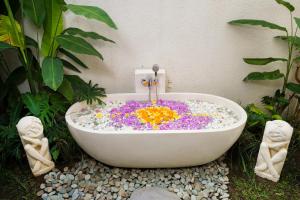 a bath tub filled with flowers in a garden at Calma Ubud Suite & Villas in Ubud