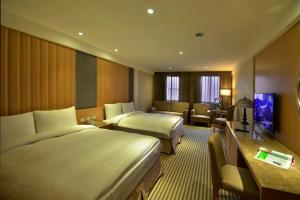 埔里にあるアポロ ホテルのベッド2台とテレビが備わるホテルルームです。