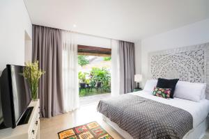 a bedroom with a bed and a tv and a window at Calma Ubud Suite & Villas in Ubud