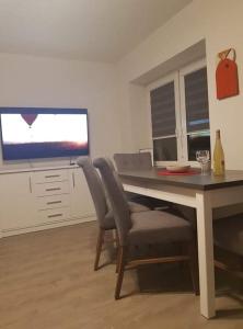 a living room with a table and chairs and a television at Apartament Malwina in Polanica-Zdrój