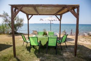 a table with chairs and an umbrella on the beach at Kefalonia Beach Hotel & Bungalows in Lixouri