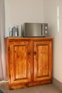 Un microondas colocado encima de un armario de madera. en Ons Dorpshuis Beaufort West, en Beaufort West