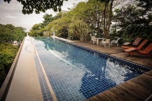a swimming pool with a wooden deck and chairs at MaliHom Private Estate in Balik Pulau