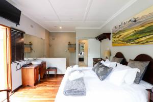 um quarto com uma cama branca e um lavatório em Arbour1 Guesthouse em George
