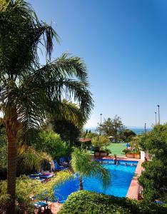 a swimming pool with palm trees and a golf course at Comfort Hotel Gardenia Sorrento Coast in Sorrento