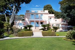 a pink house with a lawn in front of it at Grand-Hôtel du Cap-Ferrat, A Four Seasons Hotel in Saint-Jean-Cap-Ferrat