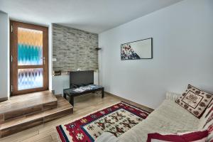 a living room with a couch and a television at Genzianella Molveno-Andalo in Molveno