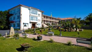 a building with benches in the grass in front of it at Aparthotel Cabicastro in Portonovo