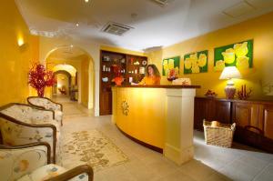 a woman standing at a counter in a yellow room at Hotel Caparena in Taormina