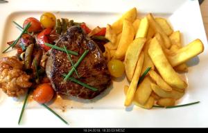 une assiette de nourriture avec steak et frites dans l'établissement Gasthaus Knudsen, à Utersum