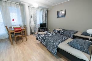 a bedroom with two beds and a table and a desk at Oulu Hotelli Apartments in Oulu