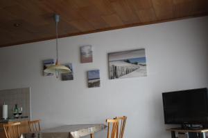 einen Esstisch mit Bildern an der Wand in der Unterkunft Wangeroogeweg 3a in Wangerland