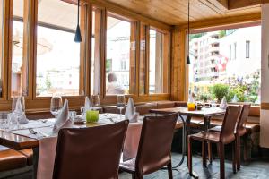 a dining room with tables and chairs and windows at Hauser Hotel St. Moritz in St. Moritz
