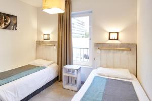 two beds in a small room with a window at Résidence Vacances Bleues Les Jardins d'Arvor in Bénodet +37 photos