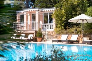 a pool with chairs and an umbrella next to a house at Grand-Hôtel du Cap-Ferrat, A Four Seasons Hotel in Saint-Jean-Cap-Ferrat