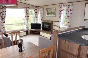 a kitchen and living room with a table and a tv at Glen View in Taynuilt