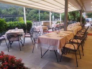 uma fila de mesas e cadeiras com toalha de mesa branca em Hotel Bettina em Mergozzo