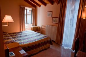 um quarto com uma cama, uma mesa e uma janela em Hotel Bettina em Mergozzo