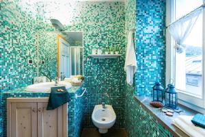 a blue tiled bathroom with a toilet and a sink at Wellness Moena in Moena