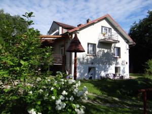 uma casa branca com varanda e algumas flores em Dom na wzgórzu em Gorlice