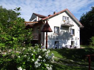 a white house with a balcony and some flowers at Dom na wzgórzu in Gorlice
