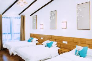 three beds in a room with white sheets and blue pillows at Zhangjiajie Tingyutang Little Yard in Zhangjiajie