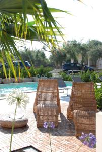 two chairs and a table next to a swimming pool at B&B Dunedorate in Punta Secca