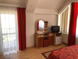 um quarto com uma cama, um espelho e cortinas vermelhas em Hotel Sucidava em Corabia