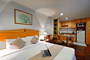 1 dormitorio con 1 cama con ordenador portátil en Admiral Suites Bangkok en Bangkok