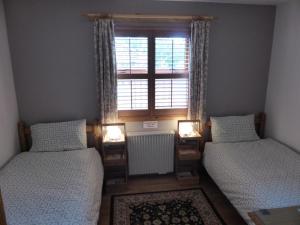 1 dormitorio con 2 camas individuales y ventana en Clifton Cottage B&B en Tyndrum