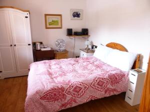 ein Schlafzimmer mit einem Bett mit einer rosa Decke in der Unterkunft Clifton Cottage B&B in Tyndrum