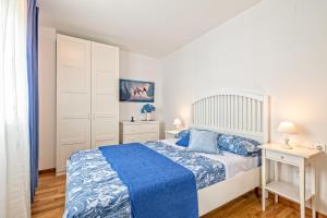 a white bedroom with a blue bed and a white cabinet at Apartamento lujo& piscina junto Barcelona Centro in Ripollet +7 photos