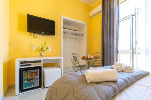 Cette chambre jaune comprend un lit et une télévision murale. dans l'établissement B&B Trianon, à Naples