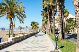 a sidewalk lined with palm trees next to the beach at Villa Amalia Suites Malaga in Málaga