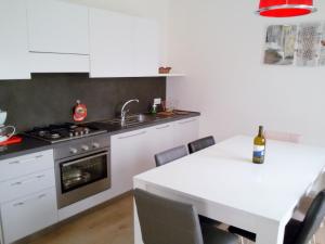 a kitchen with white cabinets and a table with a bottle of wine at Retreat Near Lake Ledro in Molina di Ledro +32 photos